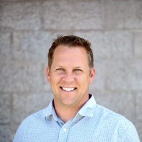 A man standing in front of a brick wall.